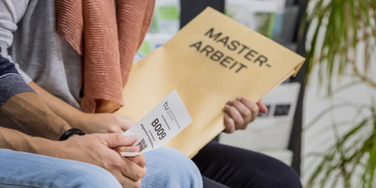 Mensch mit Master-Arbeit-Umschlag sitzt im Warteraum.